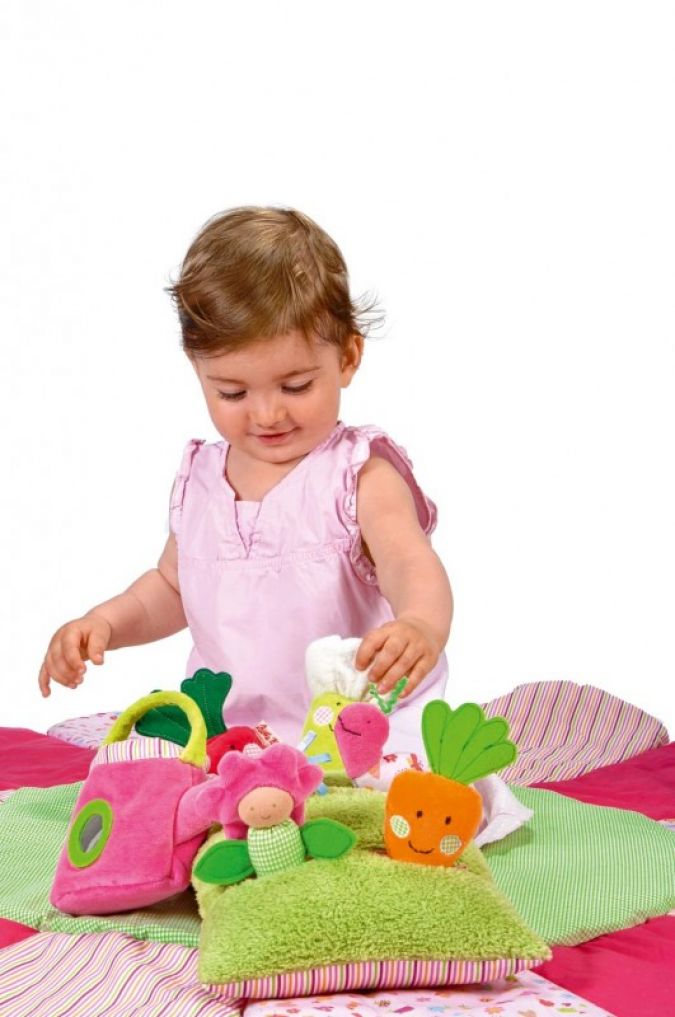Auf dem Spielkissen Wiese aus der Linie „Im Garten“ tummeln sich Radieschen, Karotte, Blume und Blumenkohl.